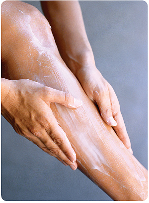 Closeup of woman spreading cream on her leg